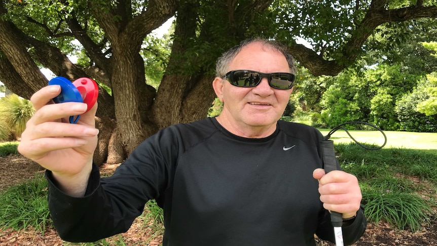 A man in sunglasses holds up castanets.