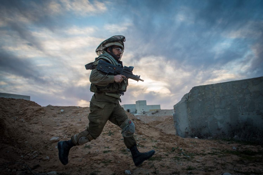 An Israeli solider running while holding a weapon.