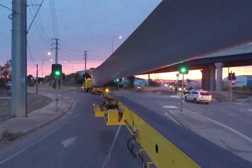 The view from the rear of the truck carrying a 65m wind turbine blade as it passes through an intersection.