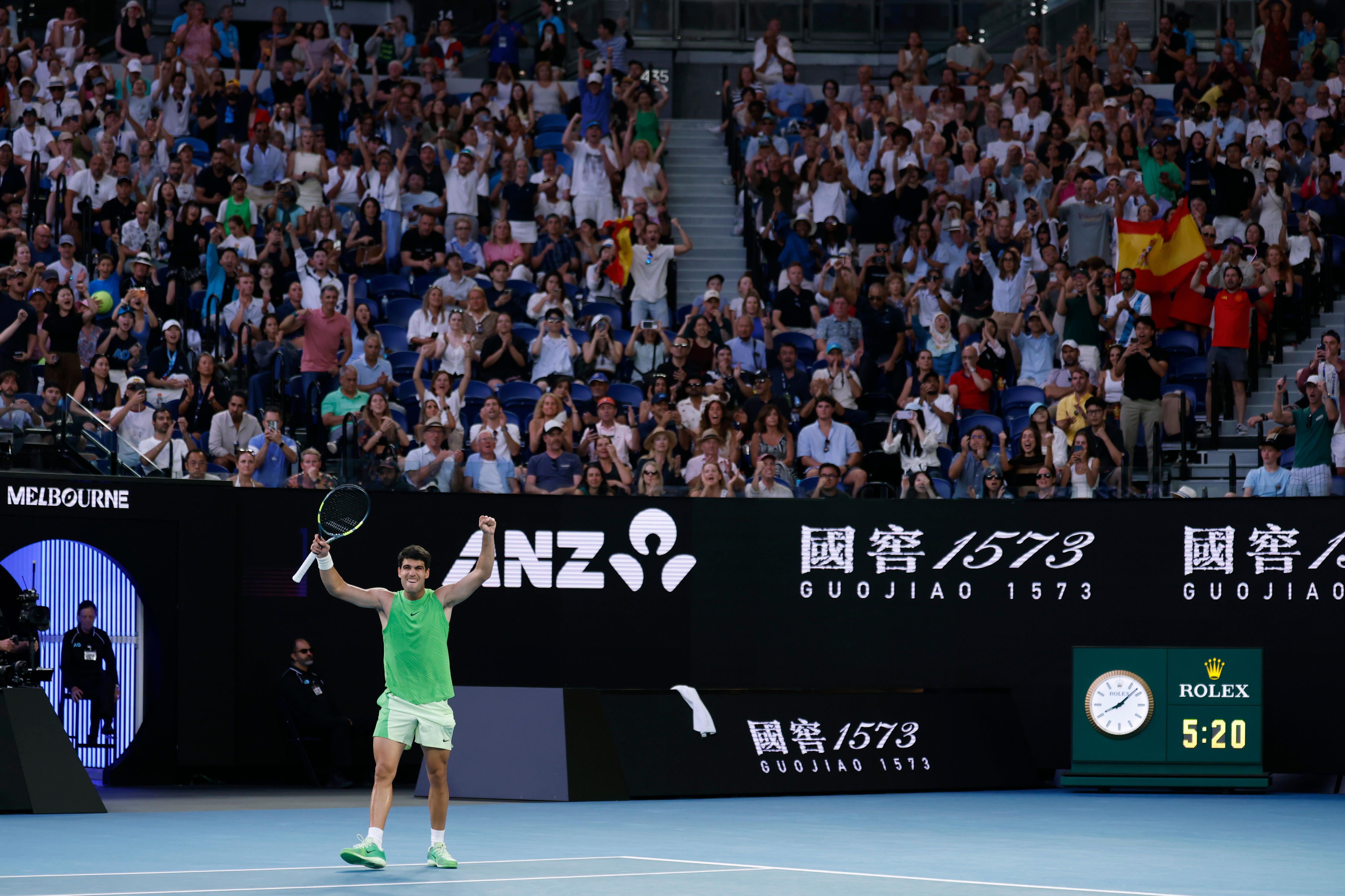 Carlos Alcaraz levanta ambos brazos en celebración mientras la multitud crece en el Abierto de Australia.