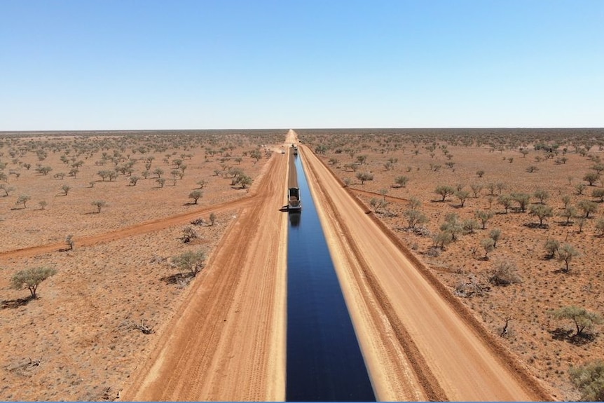 Wide outback plains with a gravel road through the middle, one lane being resealed