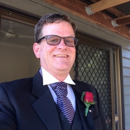 A man smiles at the camera wearing a suit.