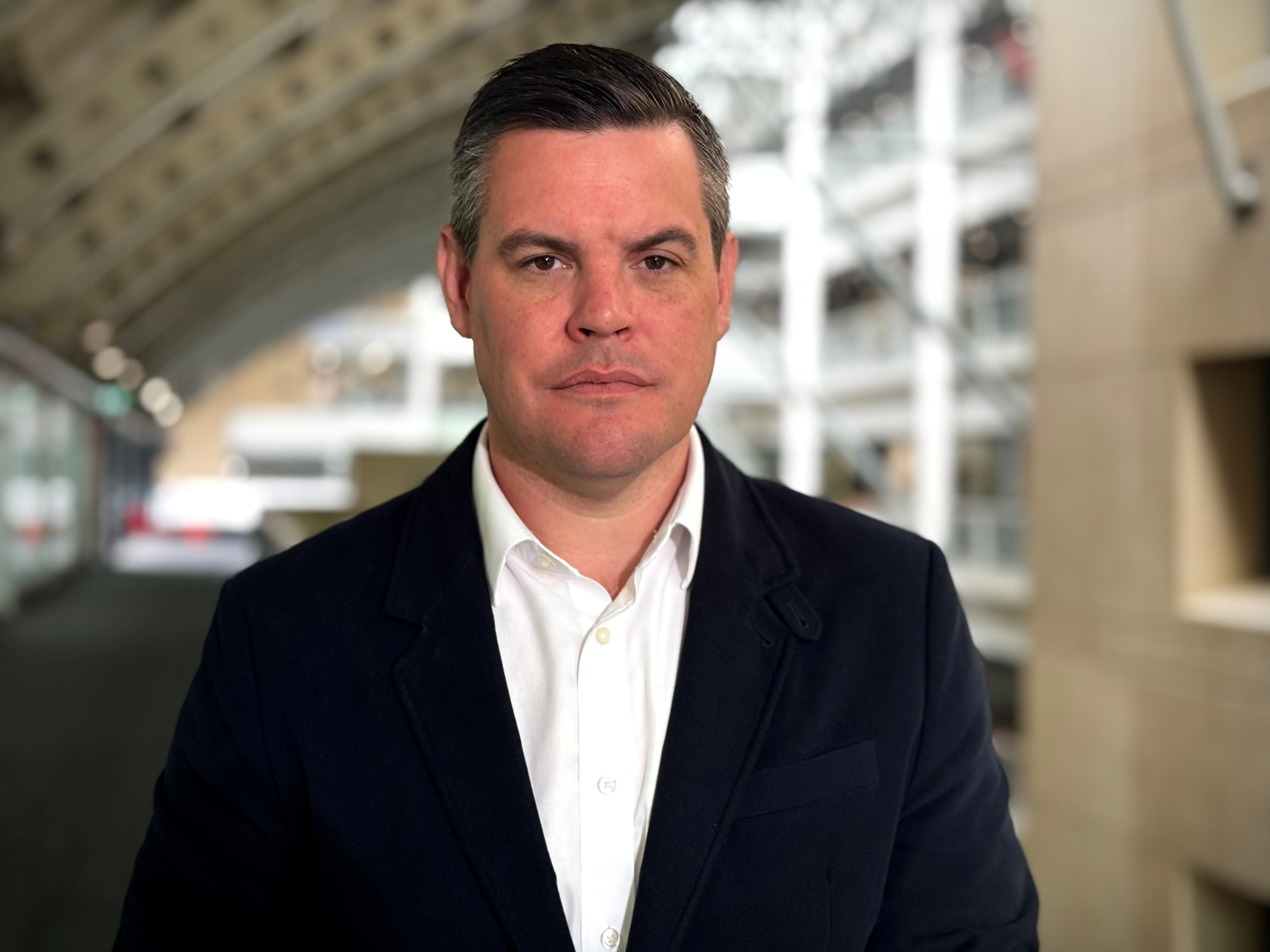 Hombre de mediana edad con cabello oscuro, vestido con camisa blanca y chaqueta oscura.