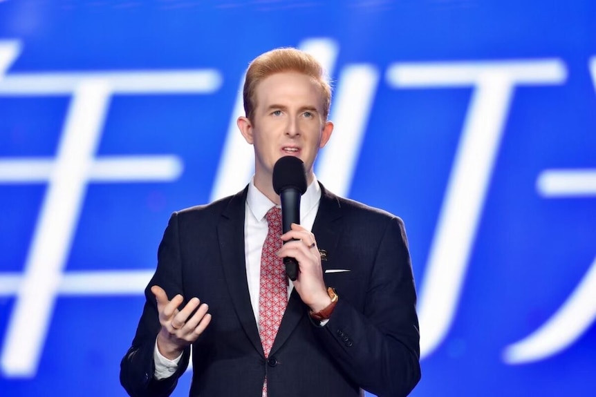 a man in a suit on stage with a microphone