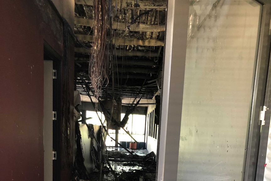 Wires hanging from the ceiling of a damaged school building after arson attack