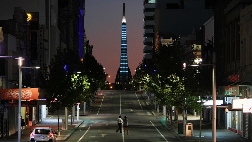 A long lens shot of a deserted streetscape with a lit up monument in the background
