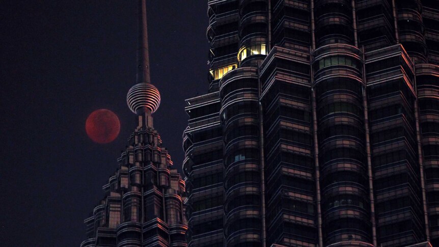 The Moon sets over the Petronas Twin Towers during a complete lunar eclipse in Kuala Lumpur, Malaysia.