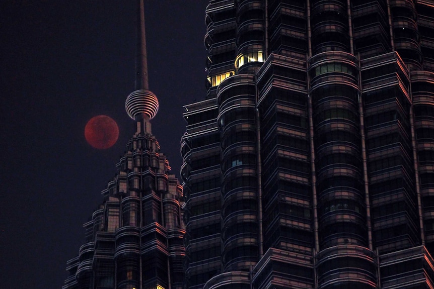 The Moon sets over the Petronas Twin Towers during a complete lunar eclipse in Kuala Lumpur, Malaysia.