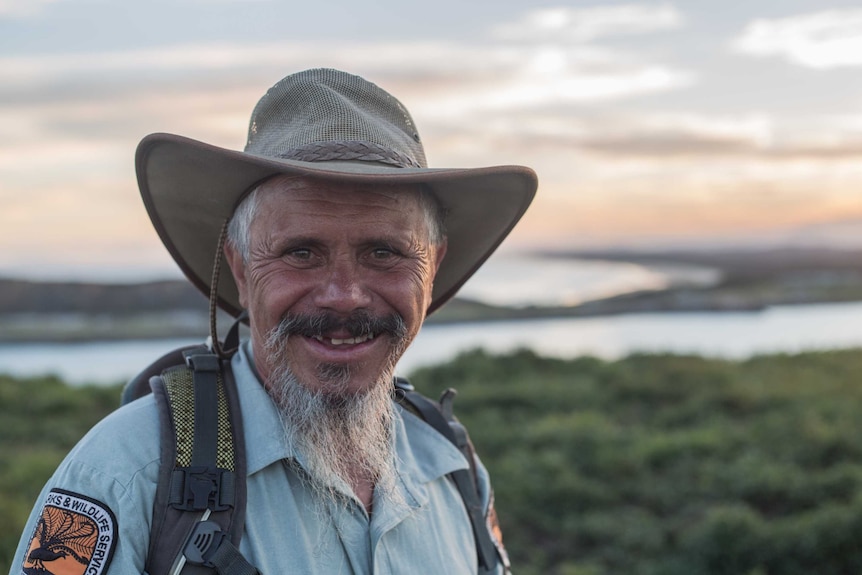 An older man with a long grey goatee smiles at camera - toothy grin - big hat rnager