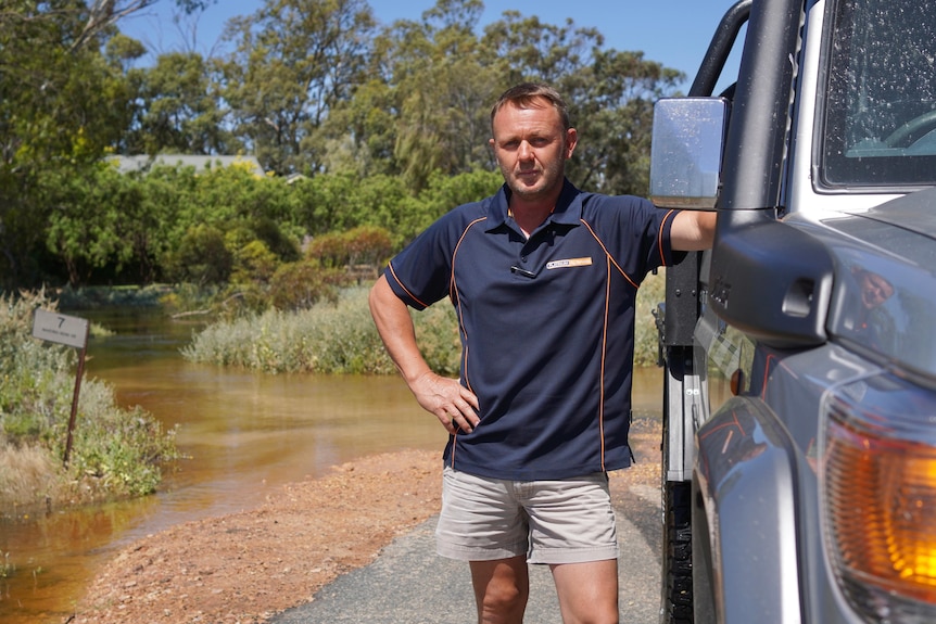 A man stands next to his submerged driveway.