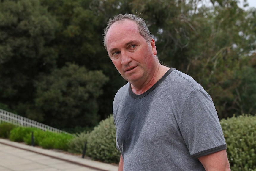 Barnaby Joyce, sweaty and red in the face, turns to look behind him. He is wearing sports attire.