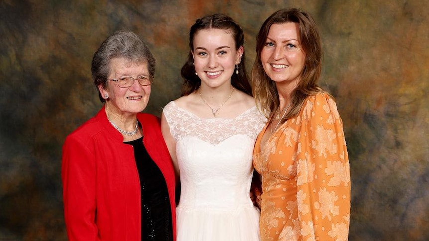 eleanor is wearing a red blazer standing next to her granddaughter tilly. tilly is wearing the deb dress her grandmother made