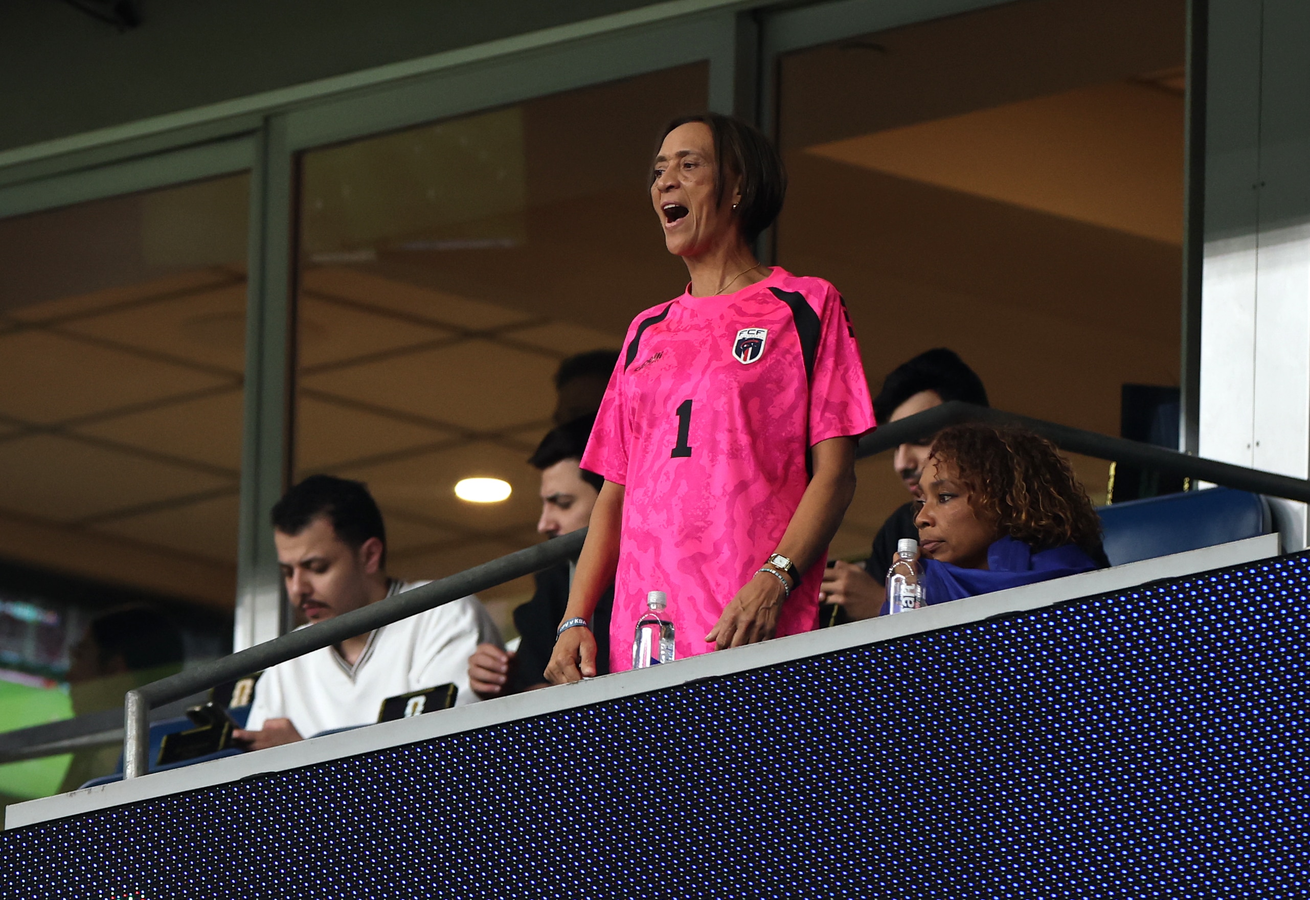 A woman stands up in the crowd at a stadium