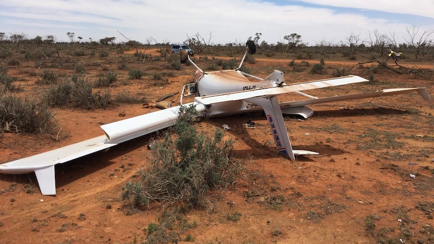 A plane crashed to the ground, rolled over on the red dirt, destroyed. the crash left two injured.