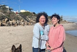 middle aged woman and young woman on a beach with a big dog.