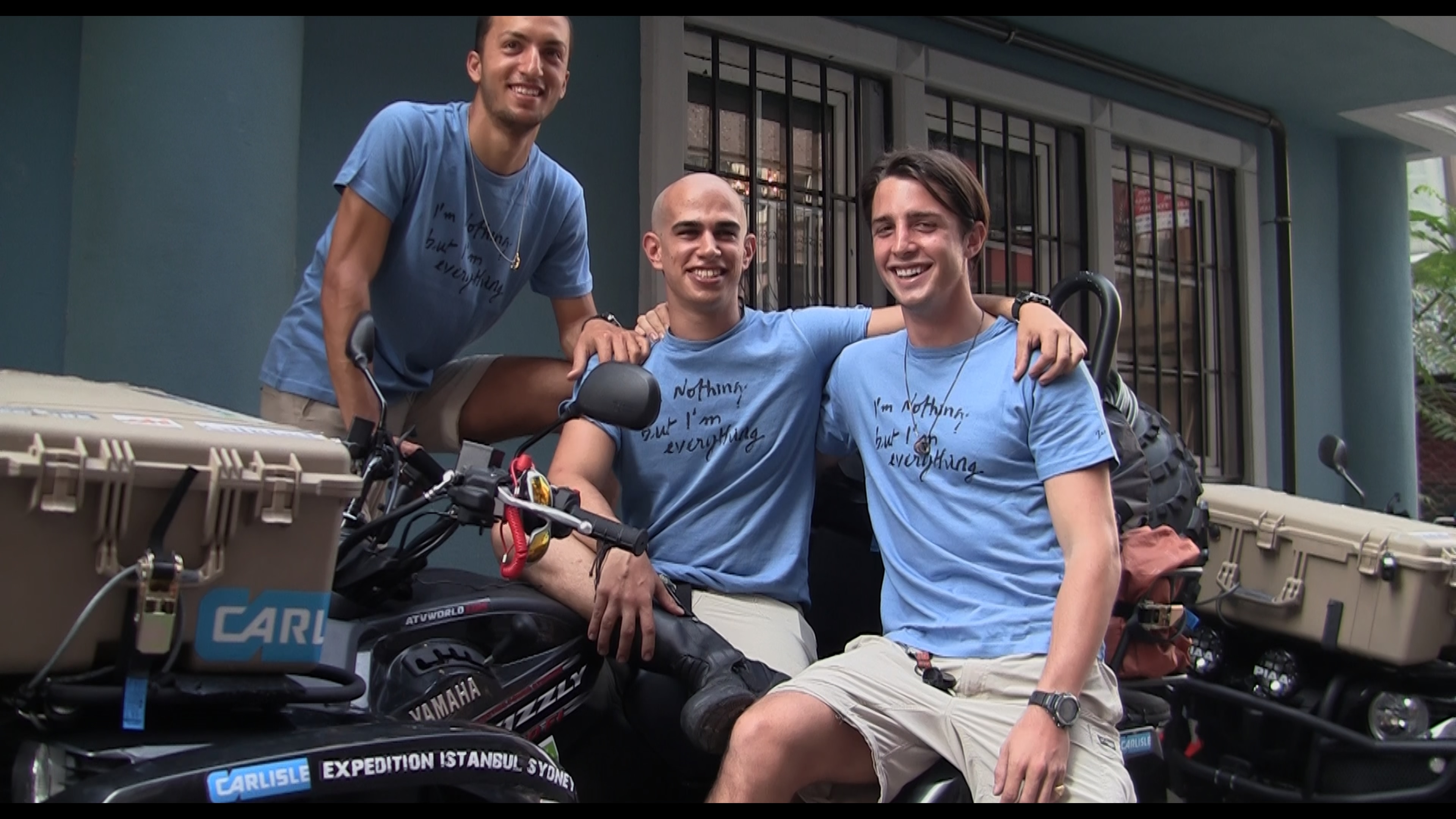 Three men in blue shirts post together
