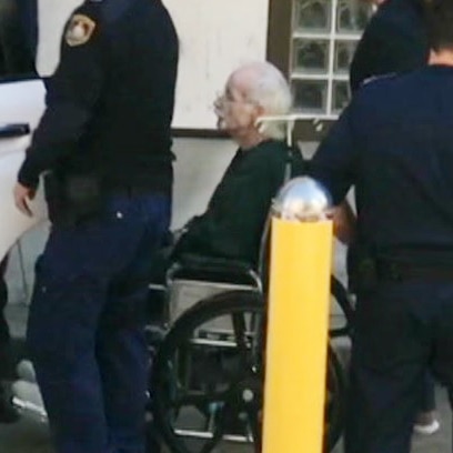 A man sitting in a wheelchair, surrounded by people