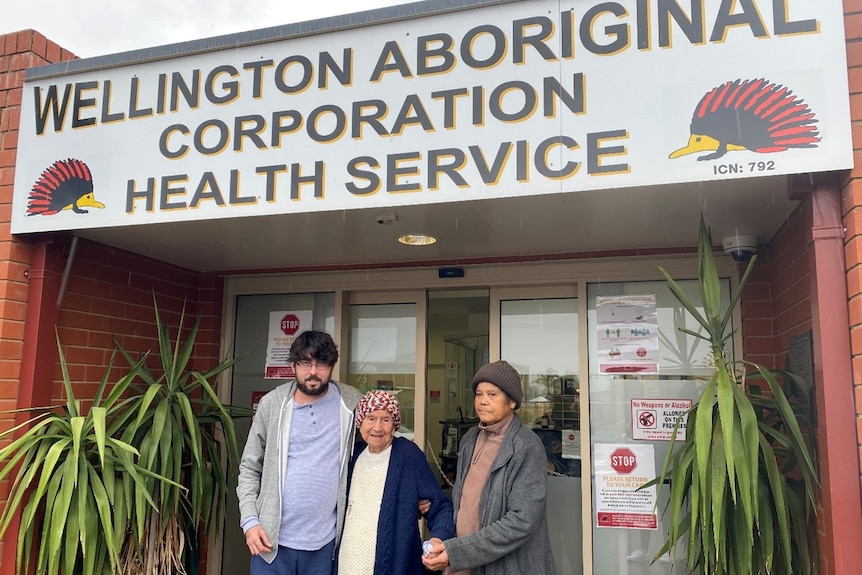 three people standing outside a health care centre