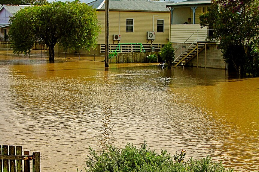 The Macleay River floods through properties in this street in Smithtown, downstream of Kempsey.
