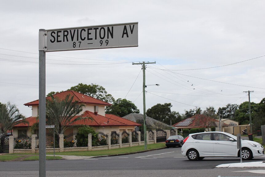 A street sign reading "Serviceton Av" with houses and cars in the background.