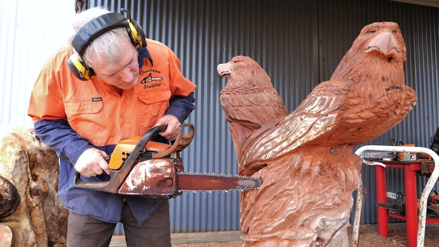 Darrel radcliffe carves a sculpture of a pair of eagles with a chainsaw.