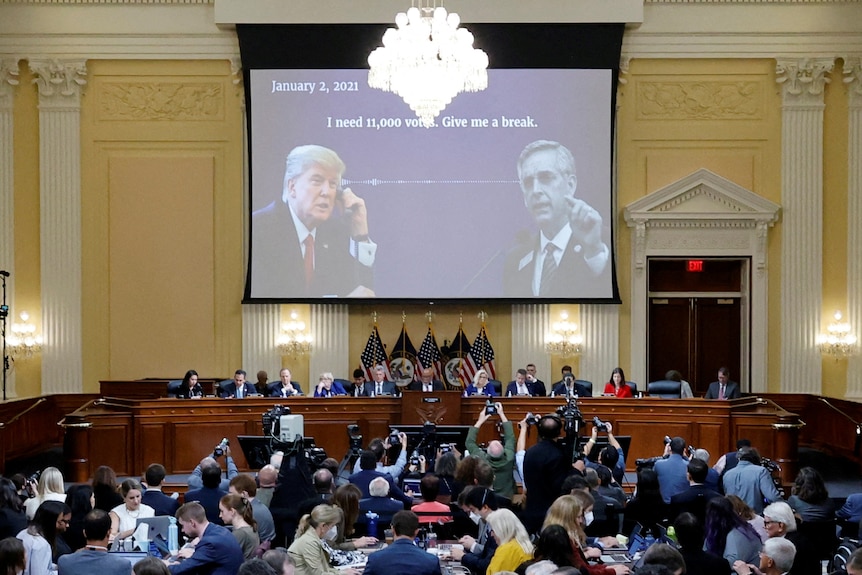 A screen shows Donald Trump on the phone to a Georgia election official with the text "I need 11,000 votes. Give me a break."