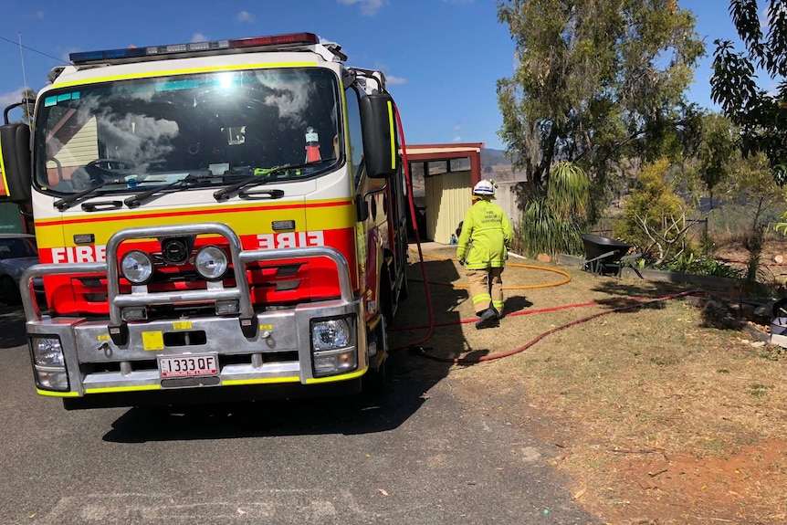 Firefighters stand next to a fire truck at a property near Woolooga.
