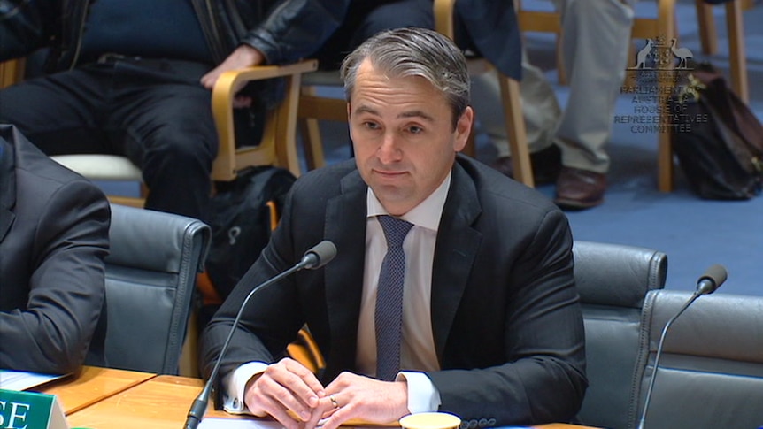 Commonwealth Bank chief executive Matt Comyn seated in front of microphone.