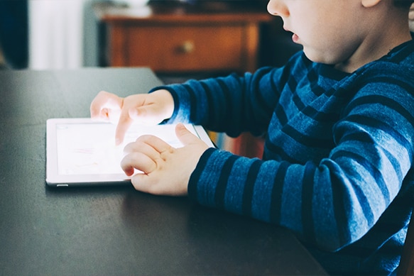 Little boy looking a bit surprised as he browses a tablet