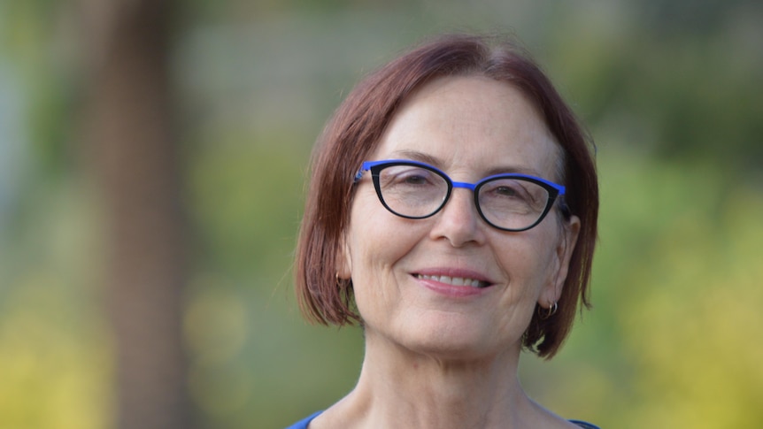 Head shot of Peters wearing glasses and smiling to camera with blurred out garden background.