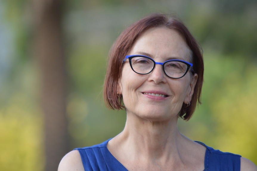 Head shot of Peters wearing glasses and smiling to camera with blurred out garden background.