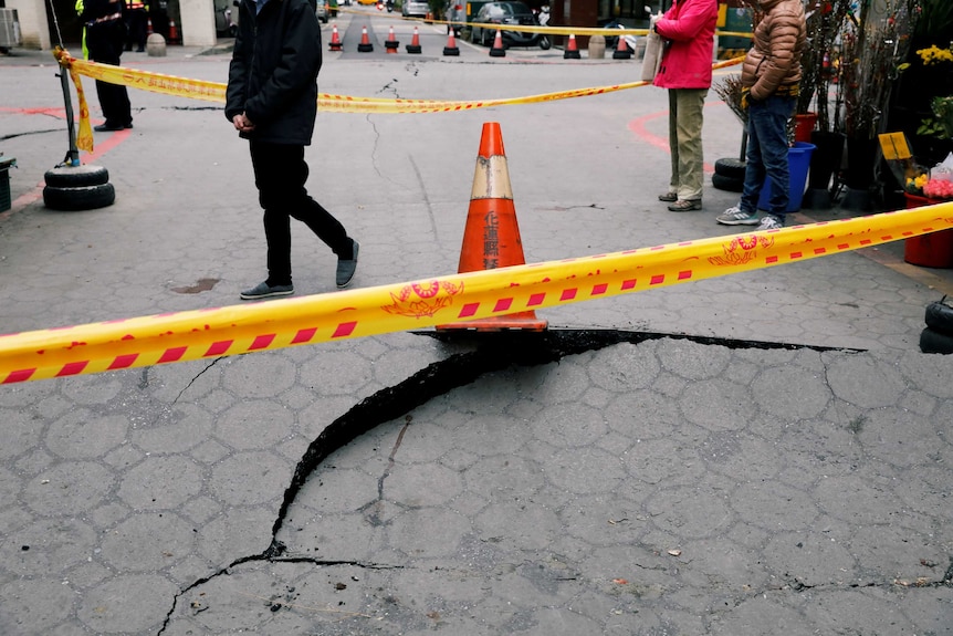 People walk by cordon paths and cracked roads.