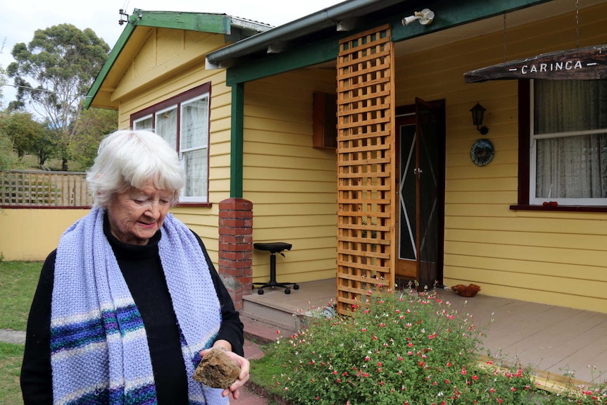 Elizabeth Coleman holds a rock outside her house at Ellendale