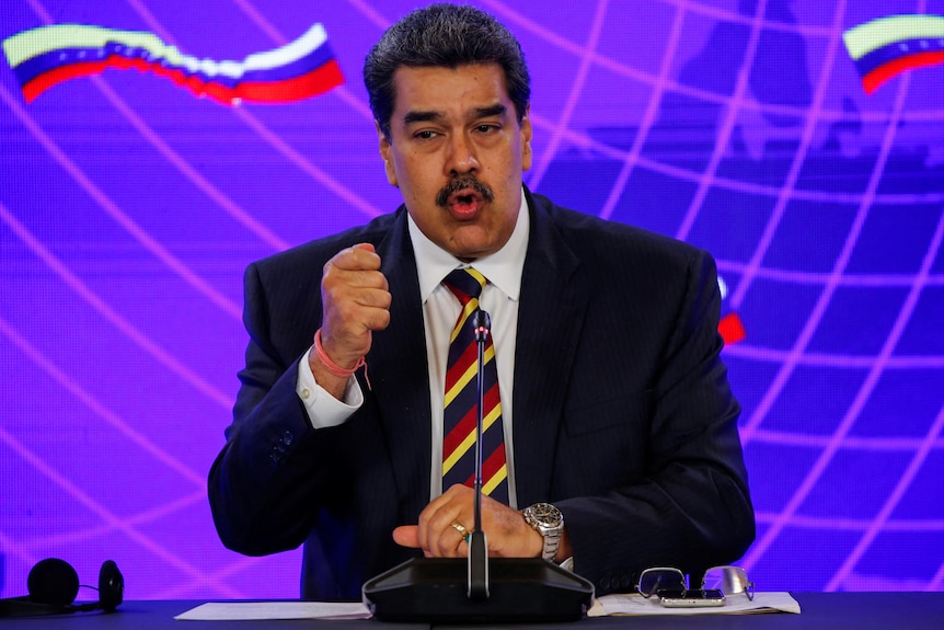 Maduro gestures as he speaks at a podium. 