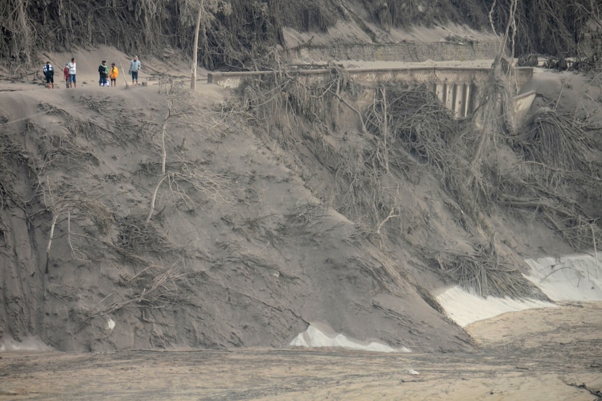 Villagers look at the broken bridge destroyed by volcanic lava flow