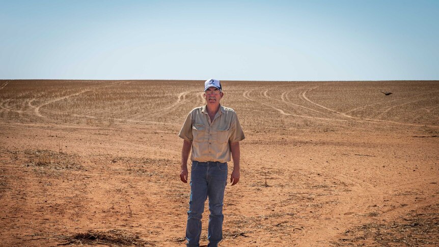 Jeff Baldock stands on a red dusty field.