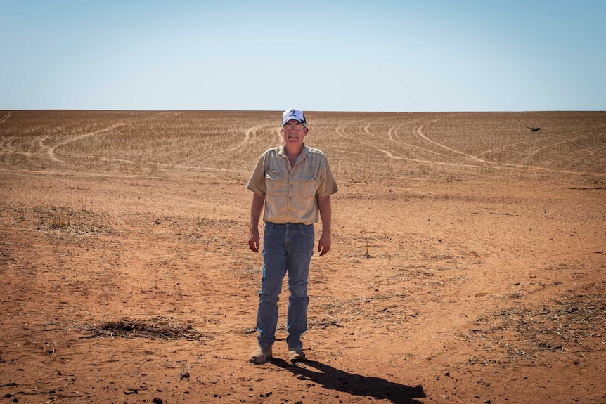 Jeff Baldock stands on an empty red dusty field.