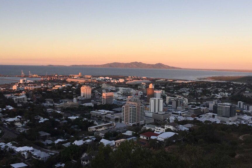 An aerial view of the Townsville central business district, port and coast as the sun sets.