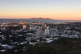 An aerial view of the Townsville central business district, port and coast as the sun sets.