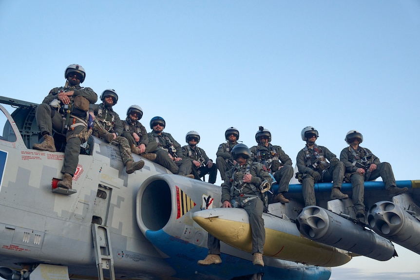 Ukrainian air force pilots pose for a photo as they sit on a Su-25 ground attack jet.