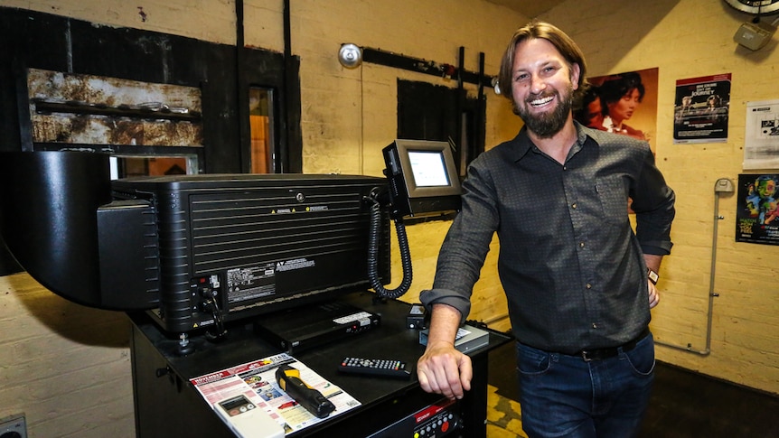 Business manager Martin Myles with the $70,000 digital projector that replaced the old reels.