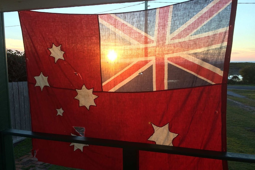 A 100-year-old red ensign flag catches the sunrise on Anzac Day in Scamander, Tasmania, 2018.