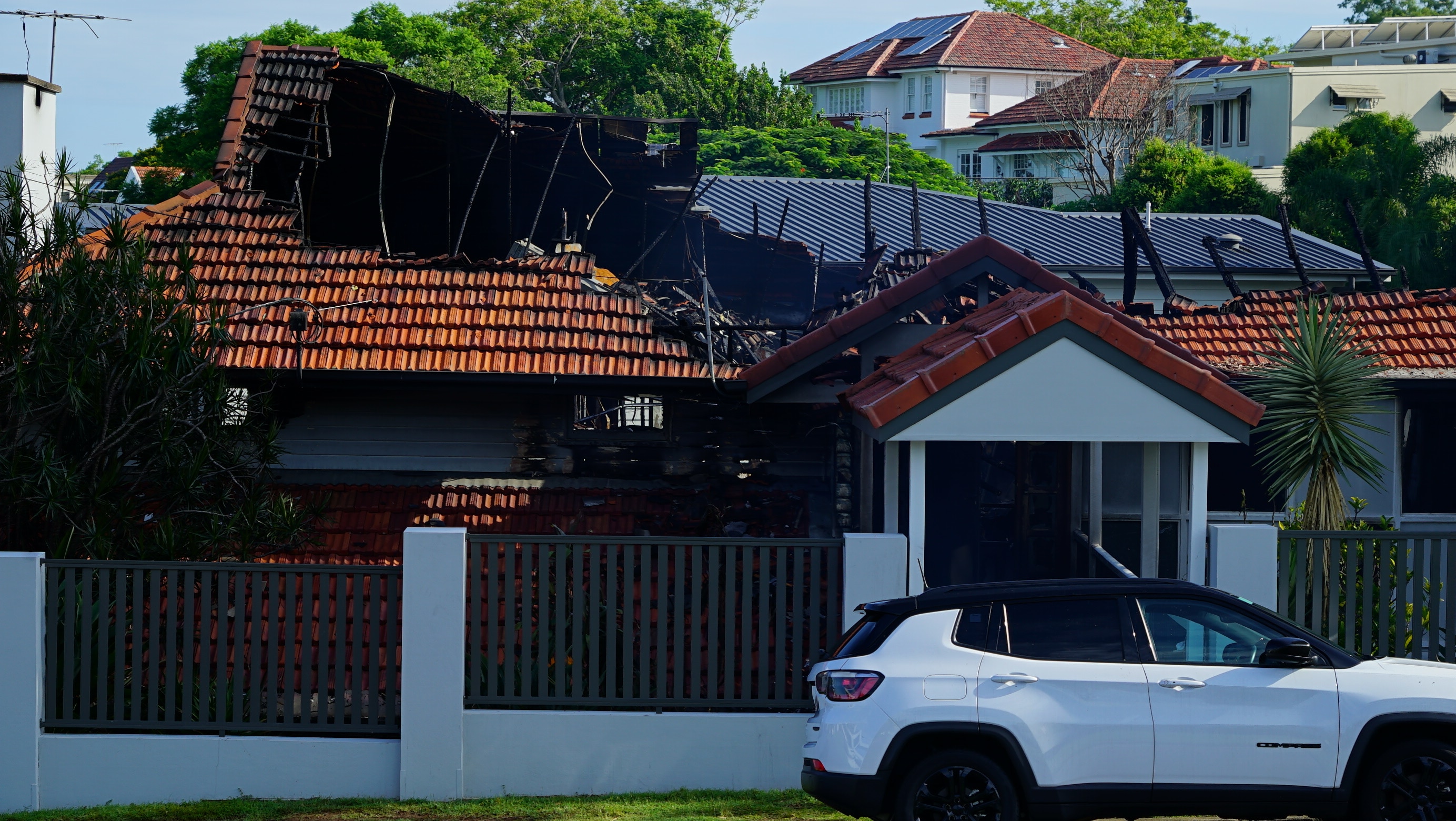 A house is blackened from fire, its roof partially destroyed