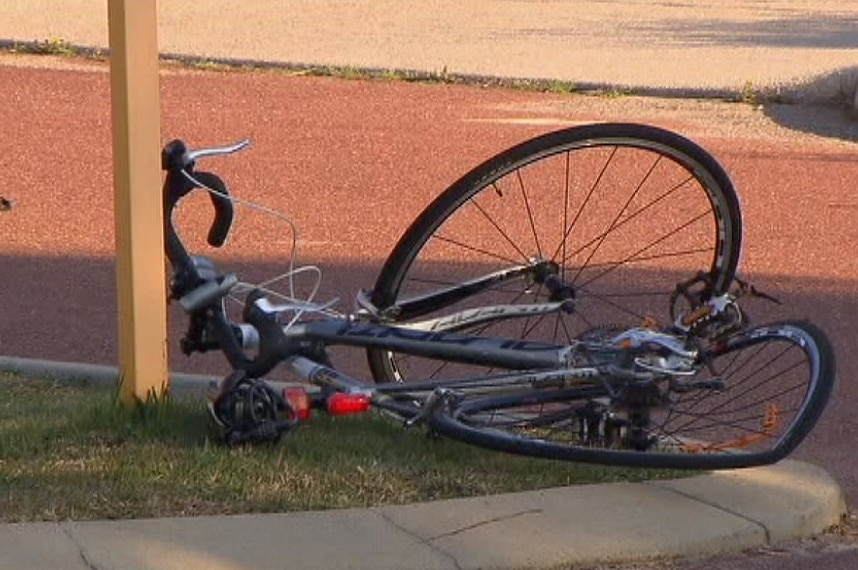 A damaged bicycle with a bent rear wheel lies on a kerb.