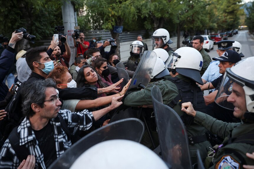 Demonstrators scuffle with riot police holding shieds, during a protest.