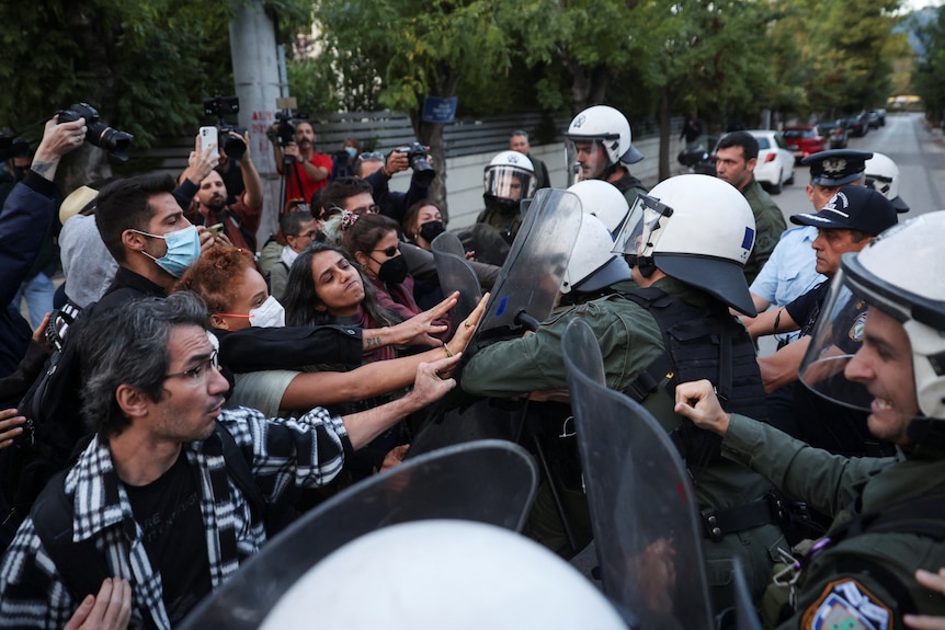 Demonstrators scuffle with riot police holding shieds, during a protest.