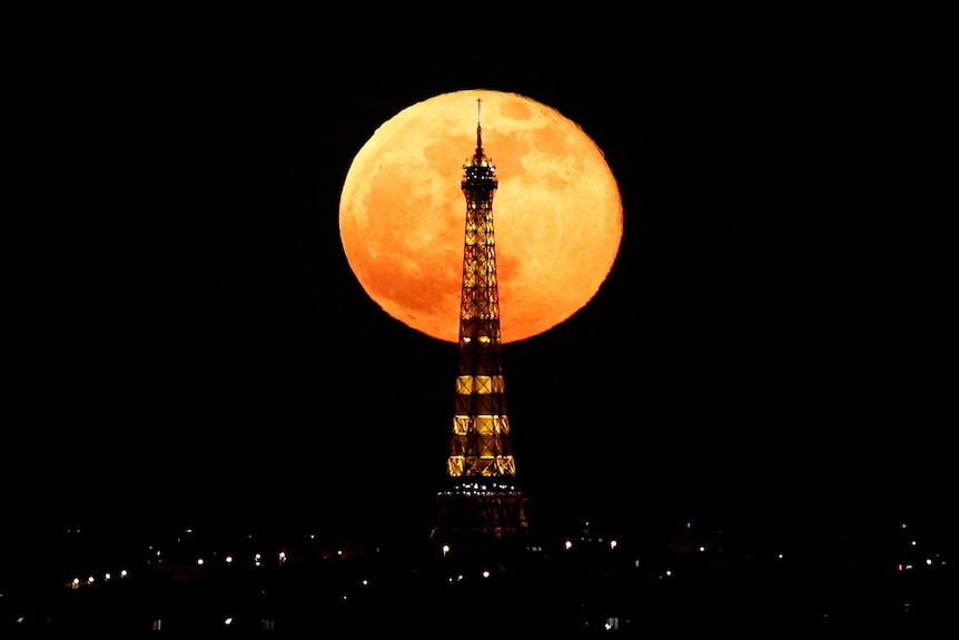The full moon, known as the super 'pink' moon, rises behind the Eiffel Tower.