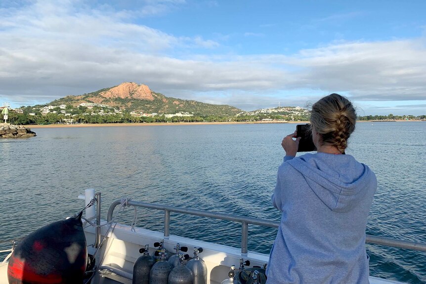 A tourist on board Paul Crocombe's reef tour boat takes a photo of the view of Townsville.