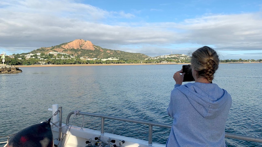 A tourist on board Paul Crocombe's reef tour boat takes a photo of the view of Townsville.
