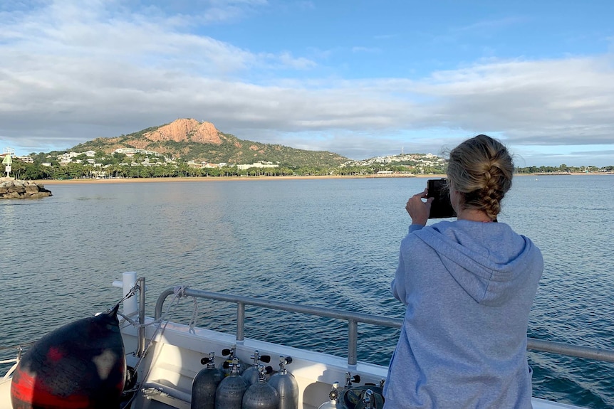 A tourist on board Paul Crocombe's reef tour boat takes a photo of the view of Townsville.